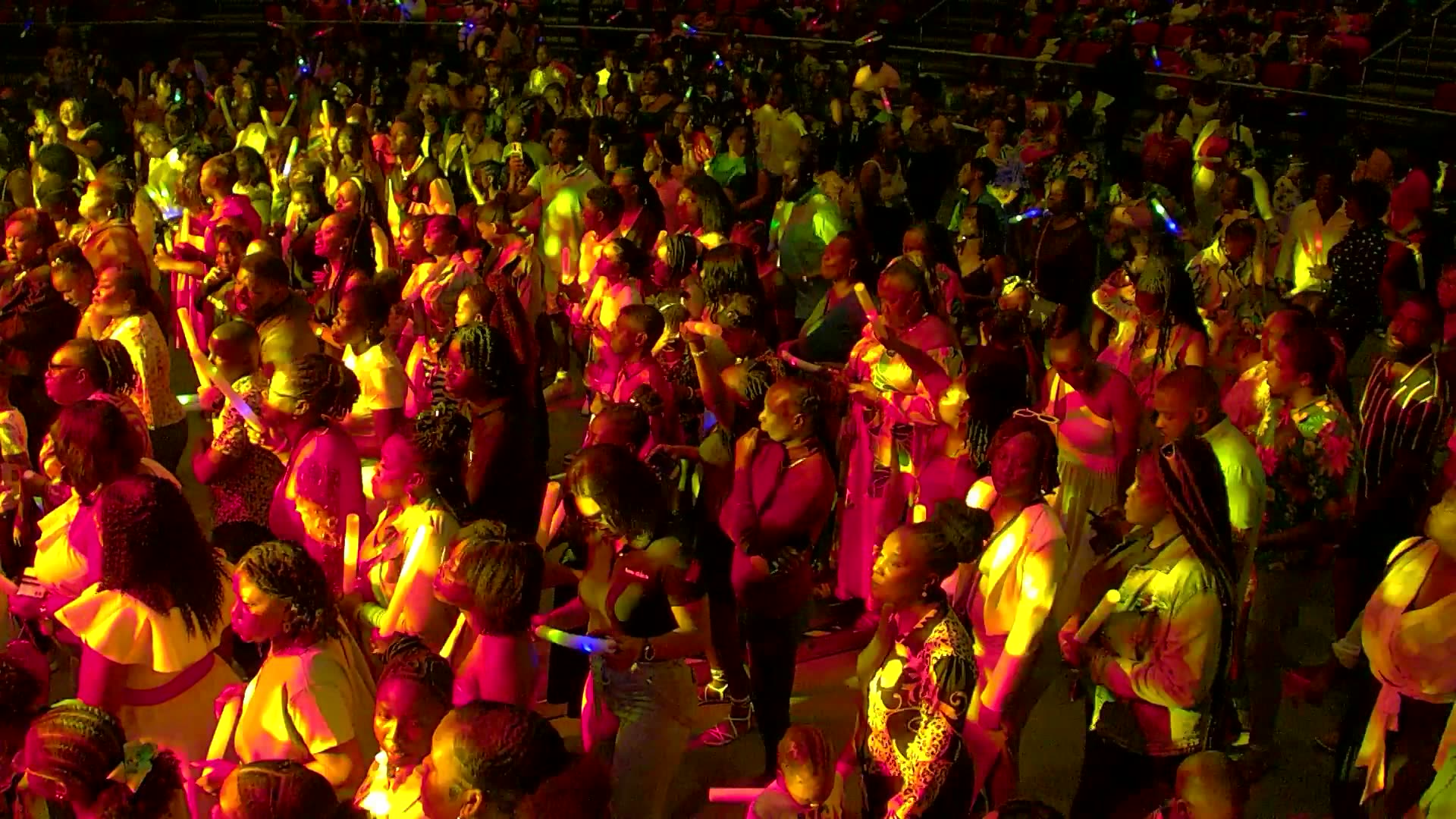 A dense congregation standing in worship under warm gold stage lighting at In His Presence 11